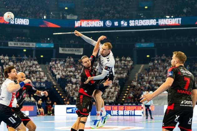 Lukas Jorgensen 25 SG Flensburg Handewitt jumps for the shot and is blocked by an MT Melsungen player Adrián Sipos 8 MT Melsungen can be seen in the background on the left, David Mandic is on the right 7 MT Melsungen MT Melsungen vs SG Flensburg Handewitt - EHF Finals Hamburg 2026 Copyright: xPhilippHeistx