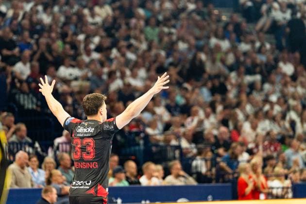 Aaron Mensing 33 MT Melsungen raises both arms in the air and cheers in front of the packed stands The backcourt player stands with his back to the camera and celebrates with the fans MT Melsungen vs SG Flensburg Handewitt - EHF Finals Hamburg 2026 Copyright: xPhilippHeistx