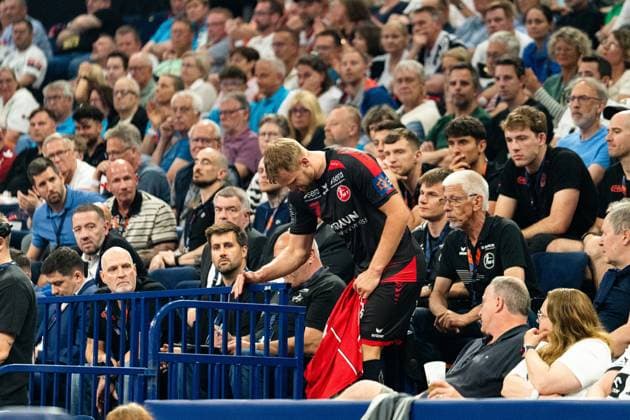 David Mandic MT Melsungen on the touchline leans forward at the barrier to the stands and holds a red towel in his hand In the background, numerous spectators follow the action MT Melsungen vs SG Flensburg Handewitt - EHF Finals Hamburg 2026 Copyright: xPhilippHeistx