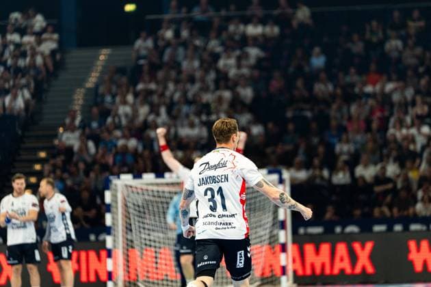 Emil Jakobsen 31 SG Flensburg Handewitt raises both fists and celebrates a goal in front of a sold-out crowd Two SG Flensburg Handewitt players and the goal can be seen in the background MT Melsungen vs SG Flensburg Handewitt - EHF Finals Hamburg 2026 Copyright: xPhilippHeistx