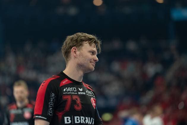 Timo Kastening 73 MT Melsungen stands on the pitch and looks to the side with a smile Spectators and another MT Melsungen player can be seen in the background MT Melsungen vs SG Flensburg Handewitt - EHF Finals Hamburg 2026 Copyright: xPhilippHeistx