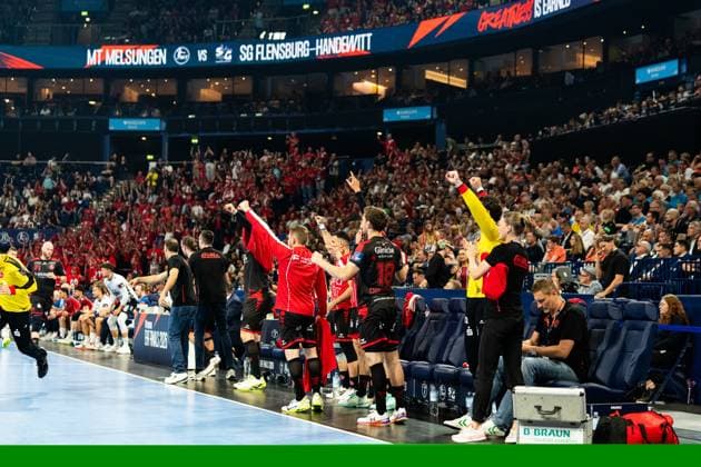 The bench and players of MT Melsungen celebrate a goal at the EHF Finals 2025 in the Barclays Arena Florian Drosten 18 MT Melsungen is recognizable in the foreground while the whole team cheers with raised fists MT Melsungen vs SG Flensburg Handewitt - EHF Finals Hamburg 2026 Copyright: xPhilippHeistx