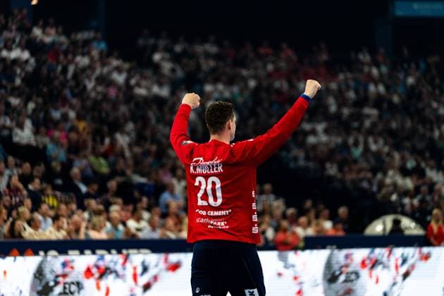 Goalkeeper Kevin Moller 20 SG Flensburg Handewitt raises both fists in the air and celebrates a save in front of a sell-out crowd The name K Moller is clearly legible on the red goalkeepers jersey Kevin Moller 20 SG Flensburg Handewitt cheers in front of a full crowd Copyright: xPhilippHeistx