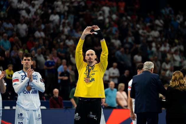Benjamin Richert 22 Montpellier HB applauds at the award ceremony, while a team-mate in a yellow goalkeeper jersey with a medal around his neck forms his hands into a heart shape above his head Both players wear bronze medals Benjamin Richert 22 Montpellier HB at the award ceremony with medal Copyright: xPhilippHeistx