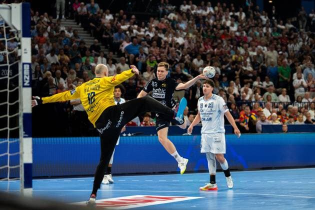 Domen Novak 63 SG Flensburg Handewitt jumps to take a shot and is blocked by goalkeeper Charles Bolzinger 12 Montpellier HB Arthur Lenne 19 Montpellier HB observes the scene in the background Domen Novak 63 SG Flensburg Handewitt taking a shot against Montpellier HB Copyright: xPhilippHeistx