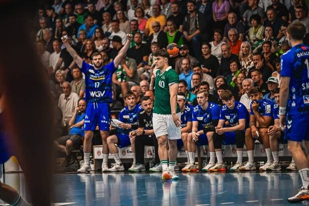 A Frisch Auf Göppingen player with the number 40 stands with the ball in his hand and prepares a throw-in In the background you can see the bench of TVB Stuttgart, including a player with the number 17 in a blue jersey Player 40 Frisch Auf Göppingen taking a throw-in against TVB Stuttgart Copyright: xspeedshotx xDorianfrickx