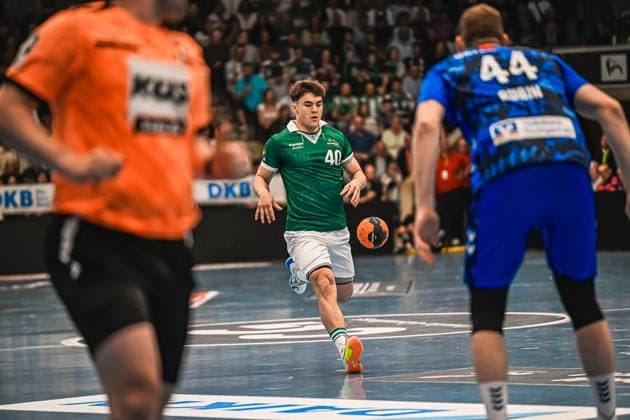 A player from Frisch Auf Göppingen with the number 40 drives the ball through the defense of TVB Stuttgart On the right is TVB player 44, on the left the Göppingen goalkeeper in the orange jersey Player 40 Frisch Auf Göppingen in attack against TVB Stuttgart Copyright: xspeedshotx xDorianfrickx