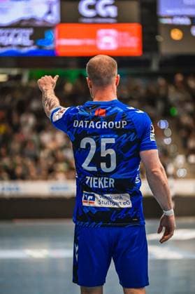 Zieker 25 TVB Stuttgart stands with his back to the camera and points with his finger in the direction of his teammates In the background you can see the packed spectator stands and the scoreboard in the hall Zieker 25 TVB Stuttgart gives hand signals on the pitch Copyright: xspeedshotx xDorianfrickx