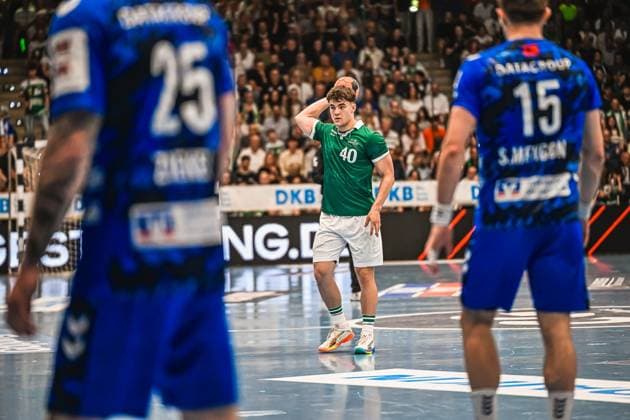 A player from Frisch Auf Göppingen 40 stands with the ball in his hand and prepares a throw Two players from TVB Stuttgart 25 and 15 stand in the foreground Frisch Auf Göppingen player 40 prepares a throw Copyright: xspeedshotx xDorianfrickx