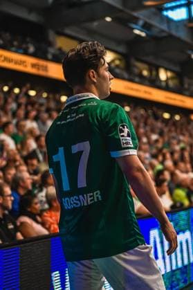 Player Gossner 17 from Frisch Auf Göppingen stands with his back to the camera in the packed arena The jersey shows the lettering 130 Jahre Edition Grün Weiß and the HBL logo Gossner 17 Frisch Auf Göppingen in the EWS Arena Copyright: xspeedshotx xDorianfrickx