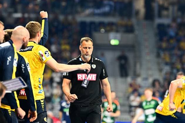 Maik Machulla, coach of the Rhein Neckar Löwen, walks concentrated along the sideline In the background, Rhein Neckar Löwen players in yellow jerseys cheer Coach Maik Machulla Rhein Neckar Löwen on the sideline Copyright: xMichaelxGelhardtx