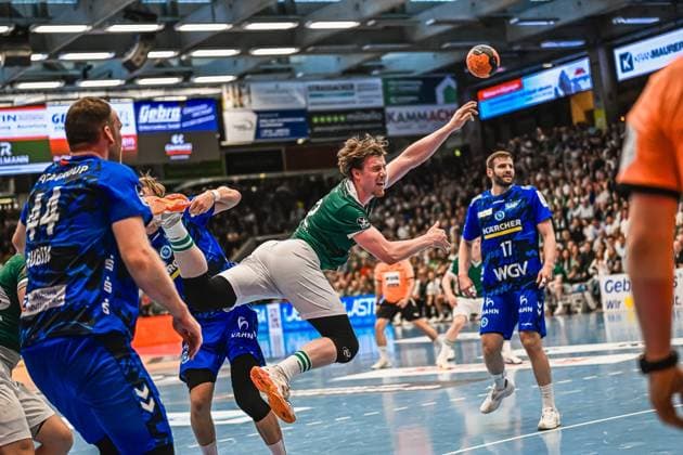 A Frisch Auf Göppingen player takes a jump shot and is pressured by the TVB Stuttgart defense Samuel Röthlisberger 17 TVB Stuttgart observes the scene in the background, Lenny Rubin 44 TVB Stuttgart can be seen on the left Frisch Auf Göppingen player taking a jump shot against TVB Stuttgart Copyright: xspeedshotx xDorianfrickx
