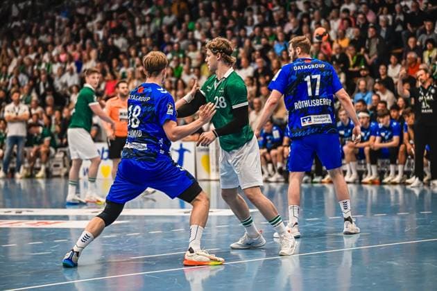 Franko Lastro 28 Frisch Auf Göppingen claims the ball in a duel between two TVB Stuttgart players, including Samuel Röthlisberger 17 TVB Stuttgart In the background, numerous spectators follow the action Franko Lastro 28 Frisch Auf Göppingen in a duel against TVB Stuttgart Copyright: xspeedshotx xDorianfrickx