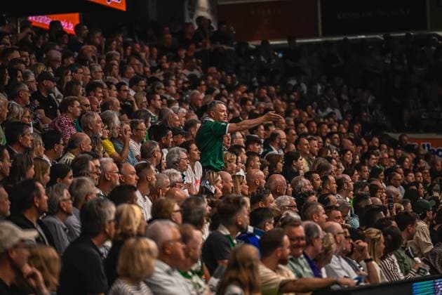 A Frisch Auf Göppingen player in a green jersey stands in front of the packed stands and stretches out his arm The hall is filled with numerous fans Frisch Auf Göppingen player gesticulates in front of full stands Copyright: xspeedshotx xDorianfrickx