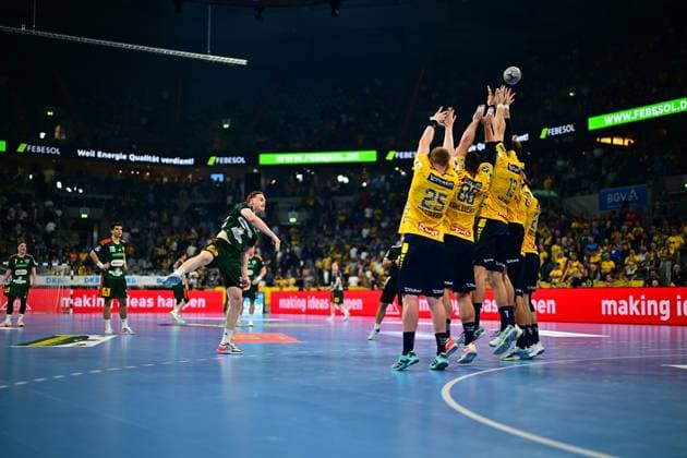 A player from TSV Hannover Burgdorf jumps for the throw and overcomes the Rhein Neckar Löwen defensive wall, in which Haukur Thrastarson 25 , Jannik Kohlbacher 80 and other players throw their arms up The ball is already in the air above the block TSV Hannover Burgdorf throw against Rhein Neckar Löwen defensive block Copyright: xMichaelxGelhardtx
