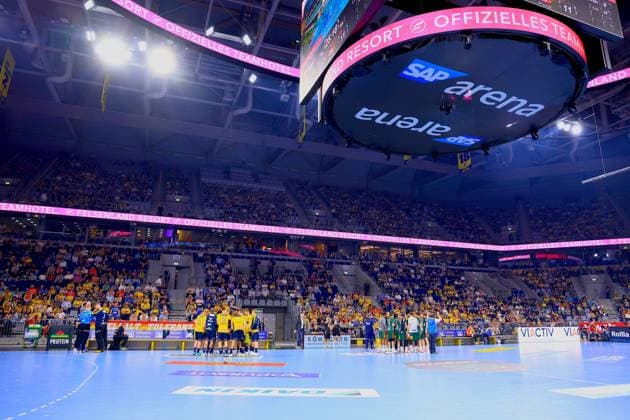 Long shot of the SAP Arena in Mannheim during a stoppage in play The Rhein Neckar Löwen yellow jerseys stand in a time-out meeting on the pitch, while the TSV Hannover Burgdorf players green goalkeeper jerseys are visible on the right side The arena is well filled with mainly yellow-clad home fans Time-out in the SAP Arena during the Rhein Neckar Löwen vs TSV Hannover Burgdorf match Copyright: xspeedshotx