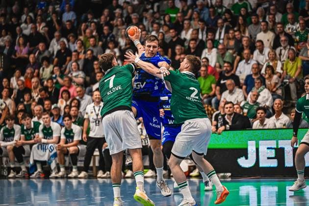 Simone Mengon 15 TVB Stuttgart jumps for the throw and is tackled by Victor Klöve 7 Frisch Auf Göppingen and Oskar Neudeck 2 Frisch Auf Göppingen The scene shows an intense duel in front of a full crowd Simone Mengon 15 TVB Stuttgart in a duel against Frisch Auf Göppingen Copyright: xspeedshotx xDorianfrickx