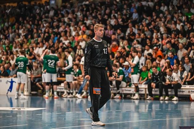 Goalkeeper Kristian Sæveras 12 Frisch Auf Göppingen runs across the pitch in a black goalkeeper jersey and looks to the side In the background you can see other Frisch Auf Göppingen players and a well-filled spectator stand Kristian Sæveras 12 Frisch Auf Göppingen runs across the pitch Copyright: xspeedshotx xDorianfrickx