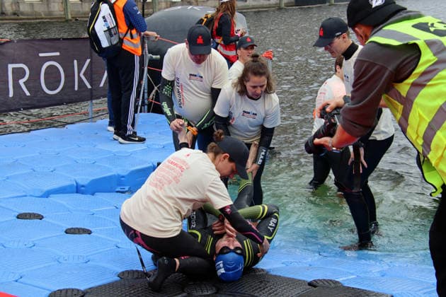 Ironman in Hamburg 2026 Helpers look after an athlete who has developed cramps in his legs after swimming