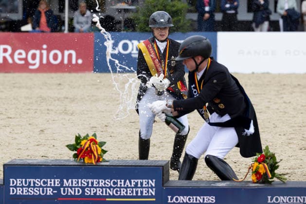 Isabell WERTH GER, left with champagne bottle in hand with Raphael NETZ GER, right at the award ceremony, champagne shower, joy, jubilation, laughter, Dressage 03 Longines Grand Optimum Prize, German Championships Grand Prix Kuer 2026, Dressage, Balve Germany, on 07 06 2026 Â