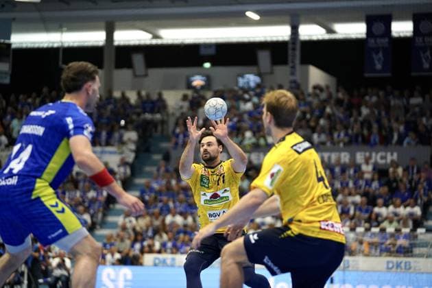 Kentin Mahé 22 VfL Gummersbach takes a throw in the SCHWALBE arena, while Teitur Einarsson 14 VfL Gummersbach is on the left and another Löwen player is on the right The stands are filled with spectators Kentin Mahé 22 VfL Gummersbach taking a throw against Rhein Neckar Löwen Copyright: xspeedshotx xD.xBarndtx