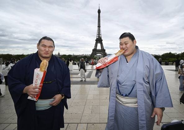 Sumo: Paris tournament Sumo grand champions Onosato (R) and Hoshoryu eat baguettes while sightseeing around Paris landmark the Eiffel Tower on June 11, 2026, ahead of a June 13-14 sumo tournament in the French capital.  A14AA0005618475P