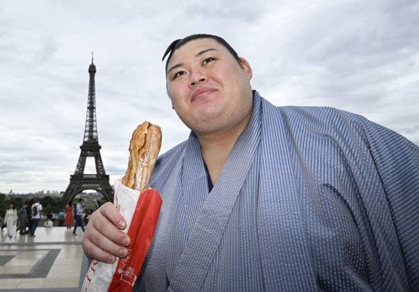 Sumo: Paris tournament Sumo grand champion Onosato is pictured with a baguette while sightseeing around Paris landmark Eiffel Tower on June 11, 2026, ahead of a June 13-14 sumo tournament in the French capital.  A14AA0005618477P