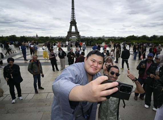 Sumo: Paris tournament Sumo grand champion Onosato takes a selfie with a tourist while sightseeing around Paris landmark Eiffel Tower on June 11, 2026, ahead of a June 13-14 sumo tournament in the French capital.  A14AA0005618482P
