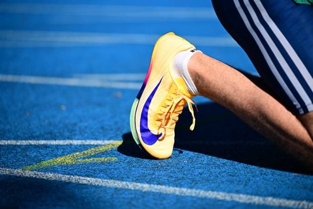 A yellow Nike sprint shoe with a blue Swoosh logo lies on the blue tartan track of the Michael Hoffmann Stadium in Mannheim The athletes bib number is not legible, personal identification is not possible Close-up of a Nike sprint shoe on the blue tartan track Copyright: xMichaelxGelhardtx