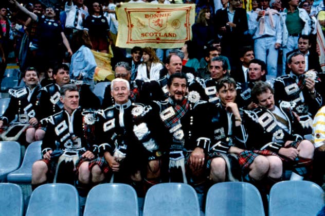 WM 1990 - Gruppenphase - Schweden vs Schottland WM 1990 in Italien, Stadio Luigi Ferraris in Genua, Gruppenphase: Schottland vs Schweden, 2:1. Schottische Fans in traditioneller Kleidung und Kilts sitzen auf der Tribüne, im Hintergrund eine Fahne mit der Aufschrift Bonnie Scotland. Genua Italien *** World Cup 1990 Group stage Sweden vs Scotland World Cup 1990 in Italy, Stadio Luigi Ferraris in Genoa, Group stage Scotland vs Sweden, 2 1 Scottish supporters in traditional clothes and Kilts sit on the Grandstand, in Background a Flag with the Inscription Bonnie Scotland Genoa Italy Copyright: xUnitedxArchivesx xSvenxSimonxSportx SVS_95020002133