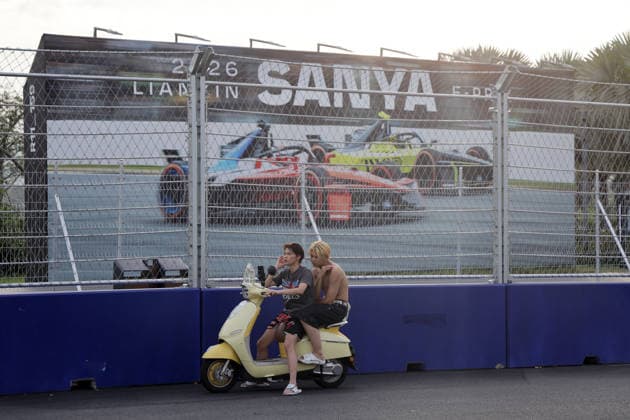 Two teenagers on their electric scooter in front of the FE promotional poster at the Fengtang-Haitang North Road intersection, Hainan Island, China, FIA Formula E World Championship Season 12, Sanya E-Prix, China, June 17, 2026, part of the race track, preparations,detected_source_language