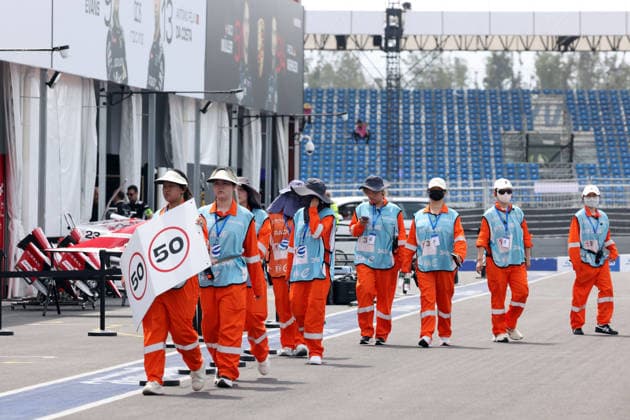 Track marshals, clad in sun-protective clothing, head to their positions in the pit lane, Sanya E-Prix, China, June 19, 2026, Hainan Island, China, FIA Formula E World Championship Season 12, ,detected_source_language