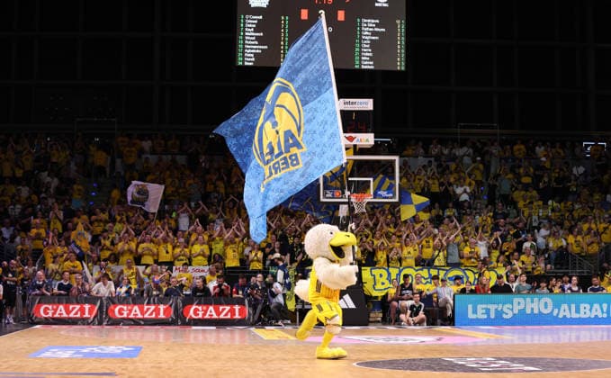 Albatros, the mascot, runs across the court carrying the Alba flag. Sports