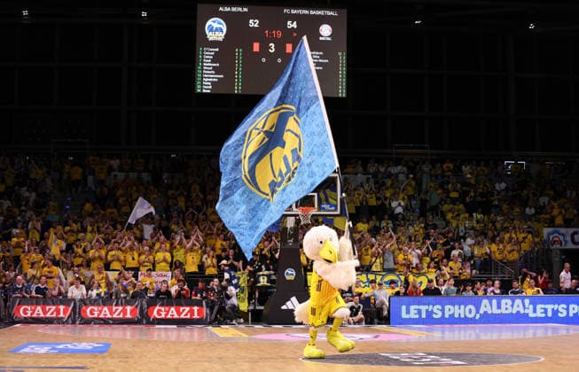 Albatros mascot with an ALBA flag on the court; Sports
