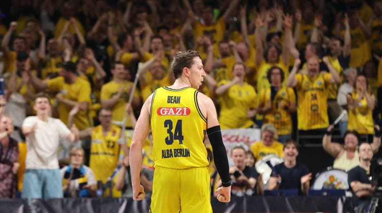 Justin Bean celebrates after a three-pointer, with Alba fans in the background