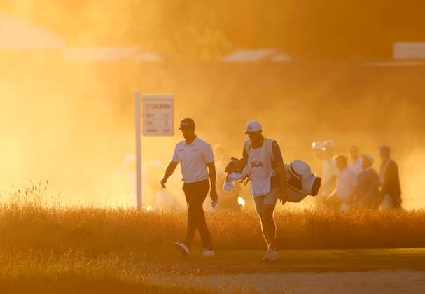 Wyndham Clark and caddie David Pelekoudas walk from the 18th tee box through rising dust from dry course conditions before sunset in the third round of the 126th U.S. Open Golf Championship at Shinnecock Hills Golf Club in Southampton, NY on Saturday, June 20, 2026.  NYC202606202024 JOHNxANGELILLO