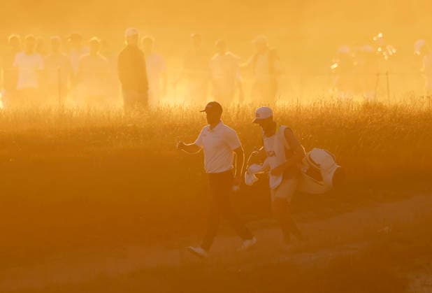 Wyndham Clark and caddie David Pelekoudas walk from the 18th tee box through rising dust from dry course conditions before sunset in the third round of the 126th U.S. Open Golf Championship at Shinnecock Hills Golf Club in Southampton, NY on Saturday, June 20, 2026.  NYC202606202026 JOHNxANGELILLO