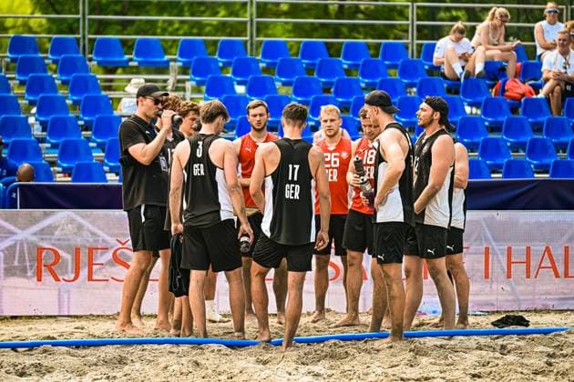 Die deutsche Beachhandball-Nationalmannschaft steht in einer Gruppe zusammen auf dem Sandfeld am Jarun See in Zagreb. Sichtbar sind u.a. LIEBECK Lennart ( 3; Deutschland), KRAUTH Tim ( 17; Deutschland), EBERT Moritz ( 26; Deutschland) und JOHN Robin ( 18; Deutschland) bei einer Auszeit oder Teambesprechung. IHF Beach Handball World Championship, WM, Weltmeisterschaft 2026, 23.06.2026, Zagreb, Jarun See *** The German national beach handball team is gathered together on the sand court at Lake Jarun in Zagreb. Among those visible are LIEBECK Lennart 3 (Germany), Tim Krauth (No. 17, Germany), Moritz Ebert (No. 26, Germany), and Robin John (No. 18, Germany) during a timeout or team huddle at the 2026 IHF Beach Handball World Championship, June 23, 2026, Zagreb, Lake Jarun,detected_source_language Copyright: xspeedshotx xDorianfrickx