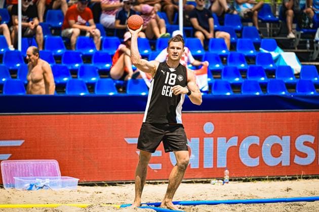 Robin John ( 18; Deutschland Beachhandball Nationalmannschaft) holt zum Wurf aus und hält den Ball mit erhobener Hand bereit. Im Hintergrund sind Zuschauer auf blauen Tribünensitzen am Jarun See in Zagreb zu sehen. IHF Beach Handball World Championship, WM, Weltmeisterschaft 2026, 23.06.2026, Zagreb, Jarun See *** Robin John 18, a member of the German national beach handball team, winds up to shoot and holds the ball ready with his hand raised. In the background, spectators can be seen in blue bleachers at Lake Jarun in Zagreb. IHF Beach Handball World Championship 2026, June 23, 2026, Zagreb, Lake Jarun,detected_source_language Copyright: xspeedshotx xDorianfrickx