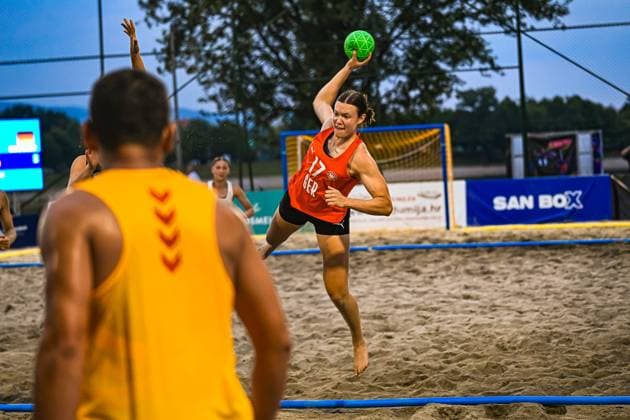 Lena Klingler ( 17; Deutsche Frauen Beachhandball Nationalmannschaft) springt im roten Trikot mit dem grünen Ball zum Wurf ab, während ein Gegenspieler im Vordergrund steht. Die Szene findet am Jarun See in Zagreb statt. IHF Beach Handball World Championship, WM, Weltmeisterschaft 2026, 23.06.2026, Zagreb, Jarun See *** Lena Klingler, a member of the German women’s beach handball national team, jumps to take a shot in her red jersey with the green ball, while an opponent stands in the foreground. The scene takes place at Lake Jarun in Zagreb during the 2026 IHF Beach Handball World Championship, June 23, 2026, Zagreb, Lake Jarun,detected_source_language Copyright: xspeedshotx xDorianfrickx