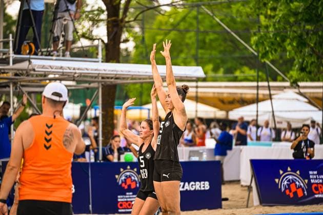 Kirsten Sophie Walter ( 5; Deutsche Frauen Beachhandball Nationalmannschaft) springt mit erhobenen Armen zum Abschluss, eine Teamkollegin unterstützt die Aktion. Im Vordergrund ist ein Gegenspieler in orangefarbenem Trikot zu sehen, im Hintergrund das Publikum am Jarun See in Zagreb. IHF Beach Handball World Championship, WM, Weltmeisterschaft 2026, 23.06.2026, Zagreb, Jarun See *** Kirsten Sophie Walter Copyright: xspeedshotx xDorianfrickx