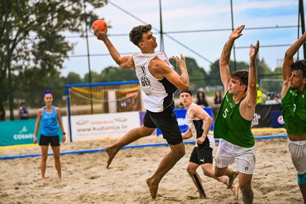 Ein Spieler der deutschen Beachhandball-Nationalmannschaft springt zum Wurf und hält den Ball hoch, während zwei italienische Abwehrspieler ( 5 und 7) die Arme strecken. Die Szene findet auf dem Sandplatz am Jarun See in Zagreb statt. IHF Beach Handball World Championship, WM, Weltmeisterschaft 2026, 23.06.2026, Zagreb, Jarun See *** A player on the German national beach handball team jumps to shoot and holds the ball aloft, while two Italian defenders, numbers 5 and 7, stretch out their arms. The scene takes place on the sand court at Lake Jarun in Zagreb during the 2026 IHF Beach Handball World Championship, June 23, 2026, Zagreb, Lake Jarun,detected_source_language Copyright: xspeedshotx xDorianfrickx
