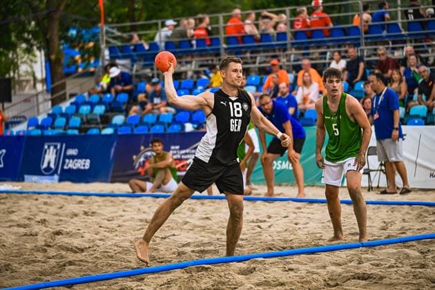 Robin John ( 18; Deutschland Beachhandball Nationalmannschaft) holt zum Wurf aus und hält den Ball hoch über dem Sand des Jarun Sees in Zagreb. Ein Gegenspieler in grünem Trikot beobachtet die Aktion aus nächster Nähe. IHF Beach Handball World Championship, WM, Weltmeisterschaft 2026, 23.06.2026, Zagreb, Jarun See *** Robin John 18, a member of the German national beach handball team, winds up for a shot and holds the ball high above the sand at Lake Jarun in Zagreb. An opponent in a green jersey watches the action up close. 2026 IHF Beach Handball World Championship, June 23, 2026, Zagreb, Lake Jarun,detected_source_language Copyright: xspeedshotx xDorianfrickx