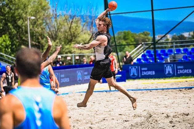 Ein Spieler der deutschen Beachhandball Nationalmannschaft springt mit dem Ball zum Wurf ab und überwindet dabei einen Gegenspieler der USA. Die Szene findet am Jarun See in Zagreb statt, im Hintergrund sind die Zagreb-Sponsorenbanden sichtbar. IHF Beach Handball World Championship, WM, Weltmeisterschaft 2026, 23.06.2026, Zagreb, Jarun See *** A player on the German national beach handball team jumps up to shoot the ball, getting past a U.S. opponent. The scene takes place at Lake Jarun in Zagreb; the Zagreb sponsor boards are visible in the background. IHF Beach Handball World Championship 2026, June 23, 2026, Zagreb, Lake Jarun,detected_source_language Copyright: xspeedshotx xDorianfrickx
