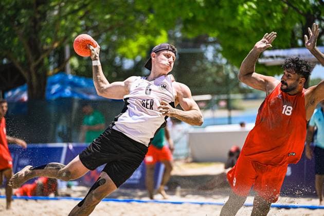 ZELSER Lars ( 6; Deutschland Beachhandball Nationalmannschaft) springt dynamisch zum Wurf und hält den Ball hoch, während Sand aufspritzt. Ein Gegenspieler mit der Nummer 18 in rotem Trikot versucht den Wurf zu blocken. IHF Beach Handball World Championship, WM, Weltmeisterschaft 2026, 23.06.2026, Zagreb, Jarun See *** ZELSER Lars 6: The German national beach handball team leaps dynamically to take a shot and holds the ball aloft as sand sprays up. An opponent wearing number 18 in a red jersey attempts to block the shot. 2026 IHF Beach Handball World Championship, June 23, 2026, Zagreb, Lake Jarun Copyright: xspeedshotx xDorianfrickx