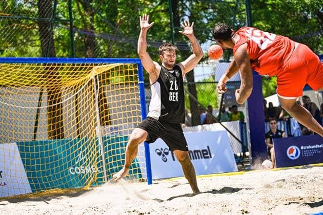 Oliver Middell ( 20; Deutschland Beachhandball Nationalmannschaft) streckt beide Arme aus und versucht einen Wurf des gegnerischen Spielers zu blocken, der Ball ist dabei direkt vor ihm in der Luft. Im Sand vor dem Tor wirbelt Staub auf, während der Angreifer im roten Trikot aus dem Sprung wirft. IHF Beach Handball World Championship, WM, Weltmeisterschaft 2026, 23.06.2026, Zagreb, Jarun See *** Oliver Middell, a member of the German national beach handball team, extends both arms and tries to block a shot by an opposing player, with the ball in the air right in front of him. Dust swirls up in the sand in front of the goal as the attacker in the red jersey shoots while jumping. IHF Beach Handball World Championship 2026, June 23, 2026, Zagreb, Lake Jarun Copyright: xspeedshotx xDorianfrickx