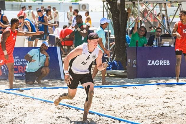 Ein Spieler der deutschen Beachhandball-Nationalmannschaft sprintet barfuß über den Sand beim IHF Beach Handball World Championship, WM, Weltmeisterschaft in Zagreb. Im Hintergrund sind Gegenspieler in roten Trikots sowie Zuschauer und das Zagreb-Banner sichtbar. IHF Beach Handball World Championship 2026, 23.06.2026, Zagreb, Jarun See *** A player on the German national beach handball team sprints barefoot across the sand at the IHF Beach Handball World Championship in Zagreb. In the background, opponents in red jerseys, spectators, and the Zagreb banner are visible. IHF Beach Handball World Championship 2026, June 23, 2026, Zagreb, Lake Jarun Copyright: xspeedshotx xDorianfrickx