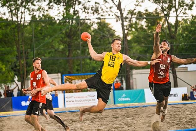 Robin John ( 18; Deutschland Beachhandball Nationalmannschaft) springt mit dem Ball in der Hand zum Wurf ab, während ein französischer Verteidiger ( 4; FRA) den Arm hochreißt. Im Sand des Jarun See-Courts in Zagreb fliegt Staub auf. IHF Beach Handball World Championship, WM, Weltmeisterschaft 2026, 23.06.2026, Zagreb, Jarun See *** Robin John 18, a member of the German national beach handball team, jumps to shoot with the ball in his hand, while a French defender 4 FRA pulls his arm up. Dust flies up from the sand on the Jarun Lake Court in Zagreb during the 2026 IHF Beach Handball World Championship, June 23, 2026, Zagreb, Jarun Lake Copyright: xspeedshotx xDorianfrickx