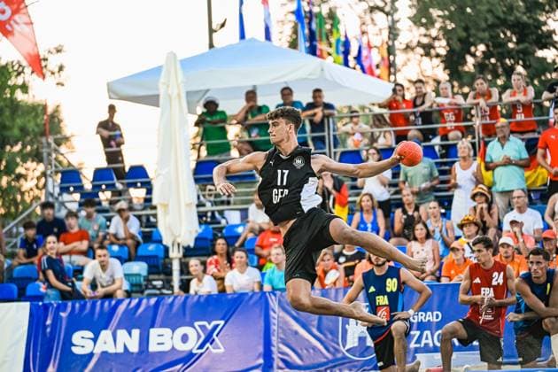 Tim Krauth ( 17; Deutschland Beachhandball Nationalmannschaft) springt hoch in die Luft und holt zum Wurf aus, der Ball ist in seiner rechten Hand. Im Hintergrund verfolgen zahlreiche Zuschauer sowie Spieler Frankreichs die Szene am Jarun See in Zagreb. IHF Beach Handball World Championship, WM, Weltmeisterschaft 2026, 23.06.2026, Zagreb, Jarun See *** Tim Krauth, 17, of the German national beach handball team, jumps high into the air and winds up to throw; the ball is in his right hand. In the background, numerous spectators and members of the French team watch the action at Lake Jarun in Zagreb during the 2026 IHF Beach Handball World Championship, June 23, 2026, Zagreb, Lake Jarun Copyright: xspeedshotx xDorianfrickx
