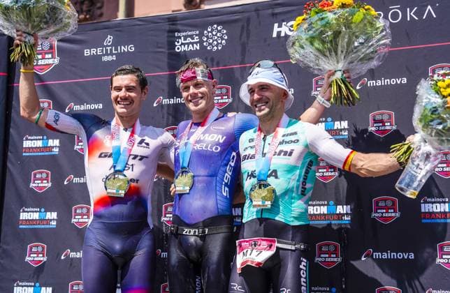 Das Siegerpodium der Herren beim Ironman Frankfurt 2026 28.06.26: Die drei Erstplatzierten der Ironman Europameisterschaft European Championship, EM, Europameisterschaft 2026 in Frankfurt am Main auf dem Podium. Von links nach rechts: Der Zweitplatzierte Gustav Iden (Norwegen), der Sieger und Europameister Casper Stornes (Norwegen) und der Drittplatzierte Benito Lopez, alle drei mit ihren Finisher-Medaillen und Blumensträußen bei der Siegerehrung auf dem Römerberg. Frankfurt Hessen Deutschland *** The men’s winners’ podium at Ironman Frankfurt 2026 06 28 26 The top three finishers of the 2026 Ironman European Championship in Frankfurt am Main on the podium. From left to right: Second-place finisher Gustav Iden of Norway, the winner and European champion Casper Stornes of Norway, and third-place finisher Benito Lopez—all three wearing their finisher medals and holding bouquets of flowers at the awards ceremony on the Römerberg in Frankfurt, Hesse, Germany JRW07434